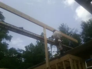Carpenter setting a ridge beam over a new addition frame — Ice Dam Removal by Roofing Brothers in Woodland Park