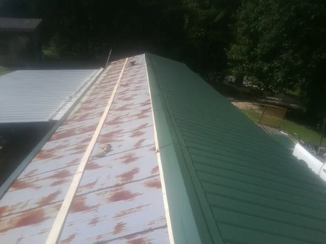 Old rusted panels beside newly installed green metal roofing — Wind Damage Roof Repair by Roofing Brothers in Woodland Park