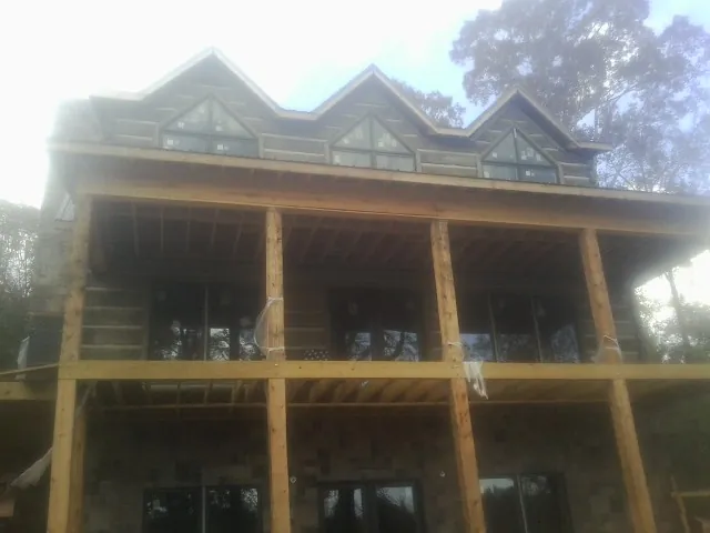 Dormers and porch framing on a large log home under construction — Roof Coating work by our crew in Woodland Park