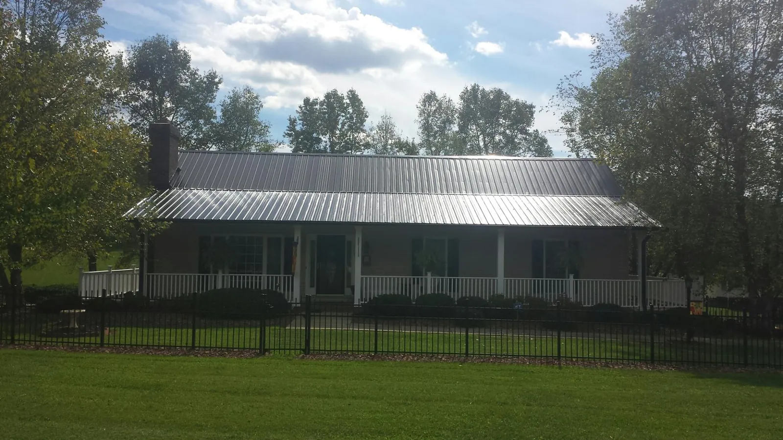 Gray metal roof on a brick ranch with a full width front porch — Gutter Guard Installation work by our crew in Woodland Park