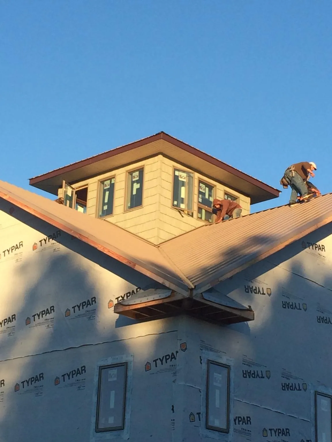 Roofers working around a rooftop cupola on a new metal roof at sunset — Roof Waterproofing in Woodland Park by Roofing Brothers